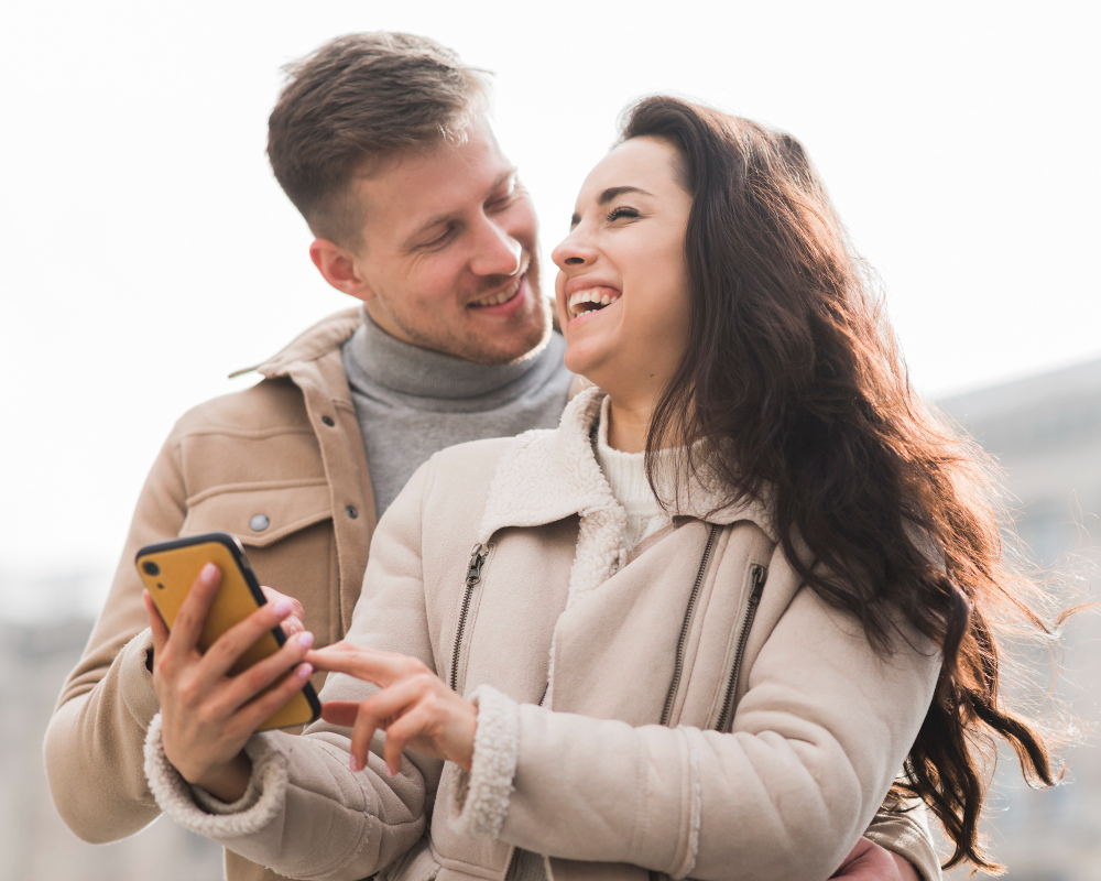 low-angle-smiley-couple-holding-smartpho